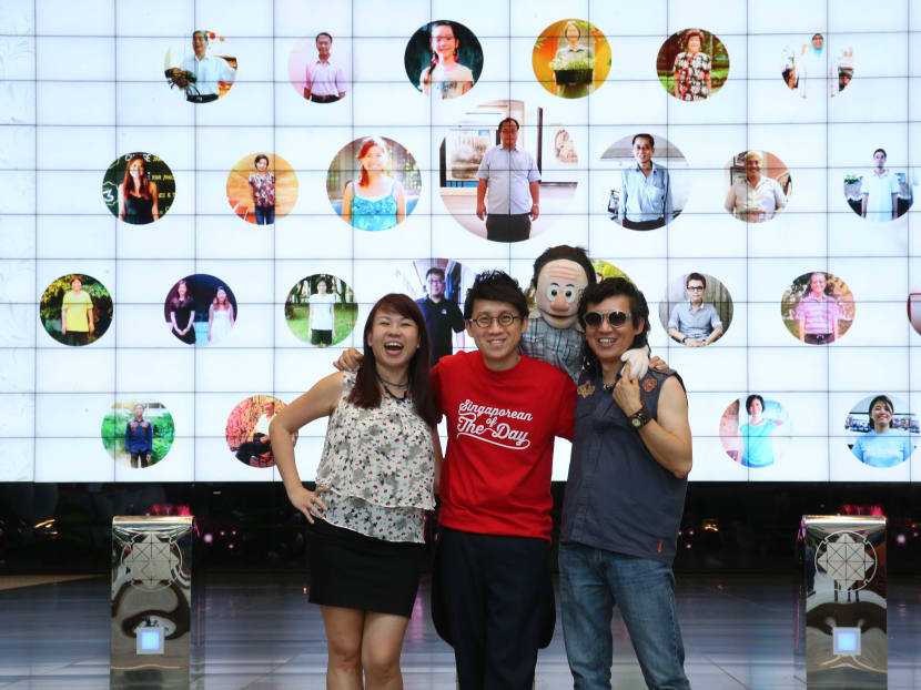 (L-R) Shannon Heo, 37, a veterinary surgeon diagnosed with multiple sclerosis, Jeff Cheong, 39, creator of Singaporean of the Day and Frankie Yeo, 52, owner of Mascots and Puppets specialists phtoographed against a giant screen projection of personalities profiled in Singaporean of the Day at Suntec City. Photo: Don Wong/TODAY