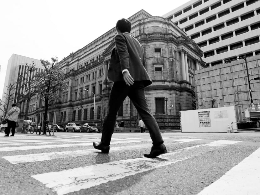 A businessman walking past the Bank of Japan building in Tokyo. Its governor Haruhiko Kuroda has initiated a policy of replacing the government bonds on the BOJ’s balance sheet once they mature. PHOTO: REUTERS