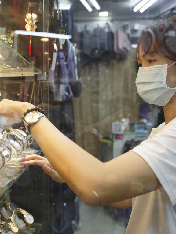 Ms Amy Tio, a bag and watch shop owner, arranges watches in her store on May 13, 2022.