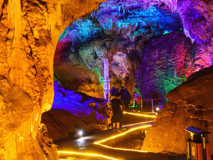 Tourists explore the brightly lit Baojiao Buffalo Cave in Mengyuan Paradise, Yunnan.