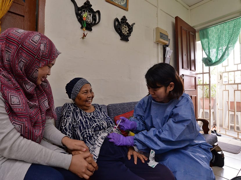 Assistant nurse clinician Chen Litang (right) delivering chemotherapy through injection to Mdm Minah Ibrahim (centre), 83, with her daughter Syaida Abdul Rahman by her side during the procedure at home, on July 25, 2017. Photo: Robin Choo/TODAY
