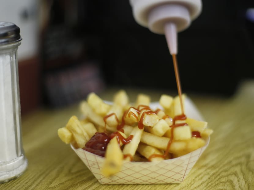 This file photo shows a customer dousing her french fries with ketchup at a concession stand. The World Health Organization say we’re eating too much sugar and should slash our intake to just 5 to 10 per cent of our overall calories. Photo: AP