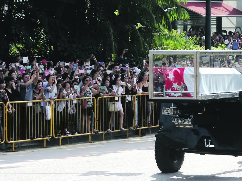 A flower is thrown by mourners observing the funeral convoy of the late Mr Lee Kuan Yew as it departs the Istana for Parliament House. Photo: Don Wong