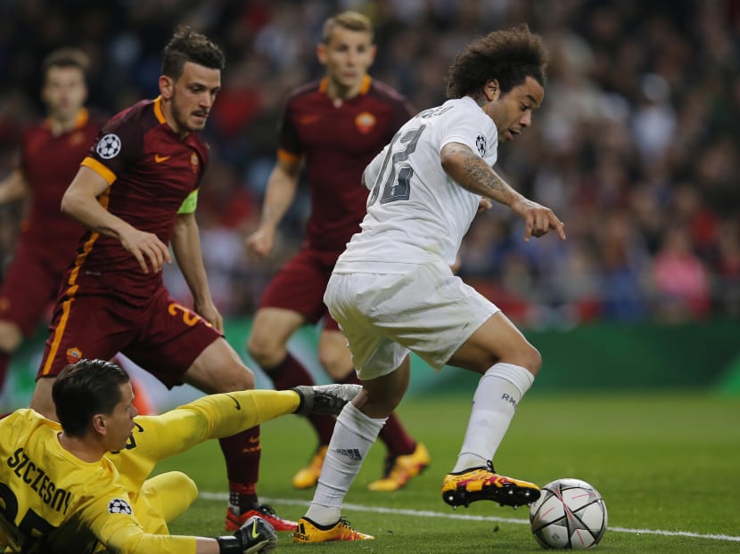 Real Madrid's Marcelo, right, tries to beat Roma goalkeeper Wojciech Szczesny during the Champions League Round of 16, second leg soccer match between Real Madrid and Roma at the Santiago Bernabeu stadium in Madrid, Tuesday March 8, 2016. Photo: AP