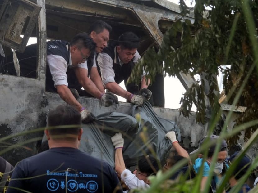 Investigators remove a body bag from the bus carrying tourists from China that crashed and caught fire along an expressway on its way to Taoyuan airport near Taipei on July 19, 2016. Photo: AFP