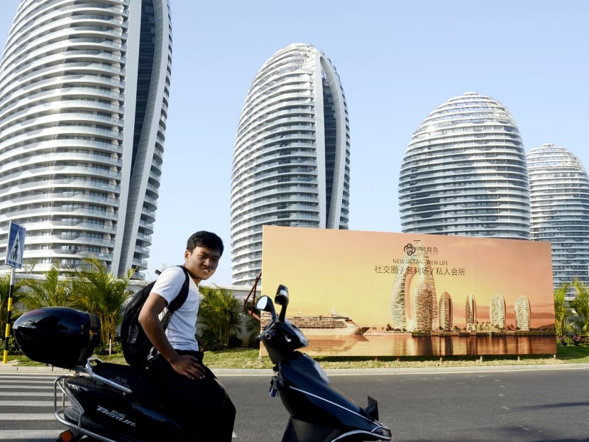 A Chinese man sitting on a motorbike in front of luxury apartment blocks at the seaside city of Sanya, in China's southern Hainan province. The surge in housing investment has raised questions about a potential bubble in the market and the implications for the long-term health of China’s economy. Photo: AFP