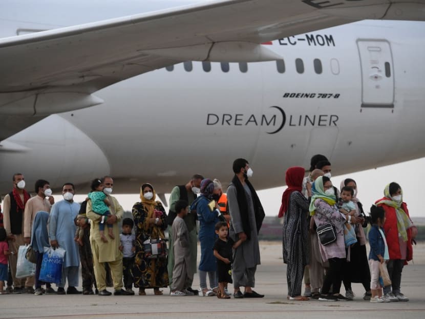 Refugees queue on the tarmac after disembarking from an evacuation flight from Kabul, at the Torrejon de Ardoz air base, 30 km from Madrid, on Aug 24, 2021. Refugees queue on the tarmac after disembarking from an evacuation flight from Kabul, at the Torrejon de Ardoz air base, 30 km from Madrid, on Aug 24, 2021.