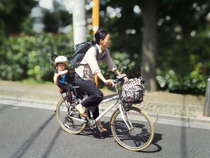 A woman riding a bike to take her daughter to a daycare facility in Tokyo. Photo: Kyodo News