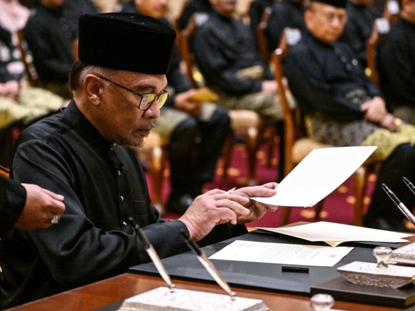 Malaysia's newly appointed Prime Minister Anwar Ibrahim signs documents after taking the oath during the swearing-in ceremony at the National Palace in Kuala Lumpur, Malaysia on November 24, 2022. Mohd Rasfan/Pool via REUTERS