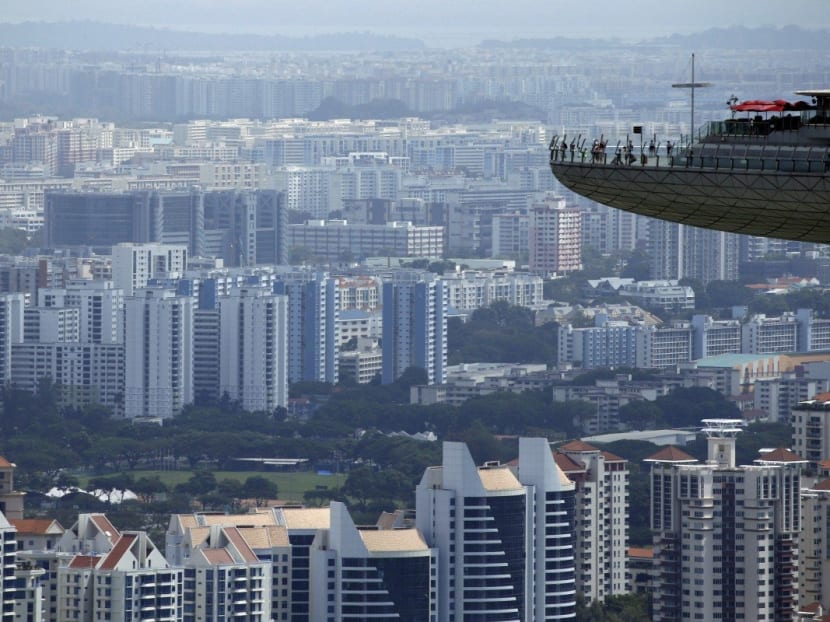 People look out from the observation tower of the Marina Bay Sands amongst public and private residential apartment buildings in Singapore.