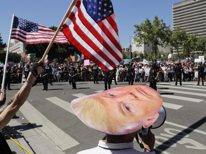 A group of President Donald Trump supporters in foreground and May Day protesters taunt each other as they are separated by police officers during a rally on May 1, 2017, in Los Angeles. Photo: AP