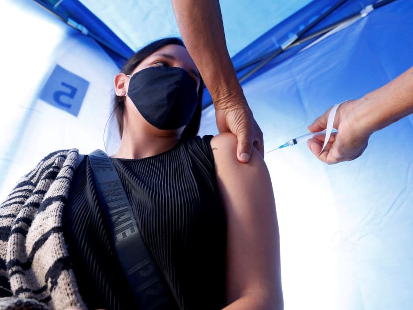 A woman receives a dose of the Pfizer-BioNTech Covid-19 vaccine at a sport stadium in Vina del Mar, Chile, on April 22, 2021. A woman receives a dose of the Pfizer-BioNTech Covid-19 vaccine at a sport stadium in Vina del Mar, Chile, on April 22, 2021.