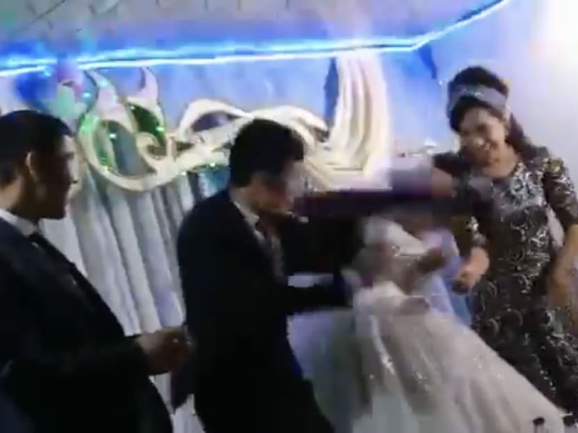 In a video posted on Twitter, a groom (second from left) hits his new bride after losing to her in a game at their wedding.