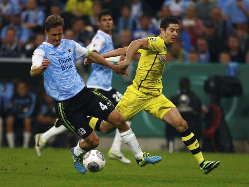 Borussia Dortmund's Robert Lewandowski (right) fights for the ball with Kai Buelow of TSV 1860 Munich during their second round German soccer cup (DFB-Pokal) match in Munich September 24, 2013. Photo: Reuters