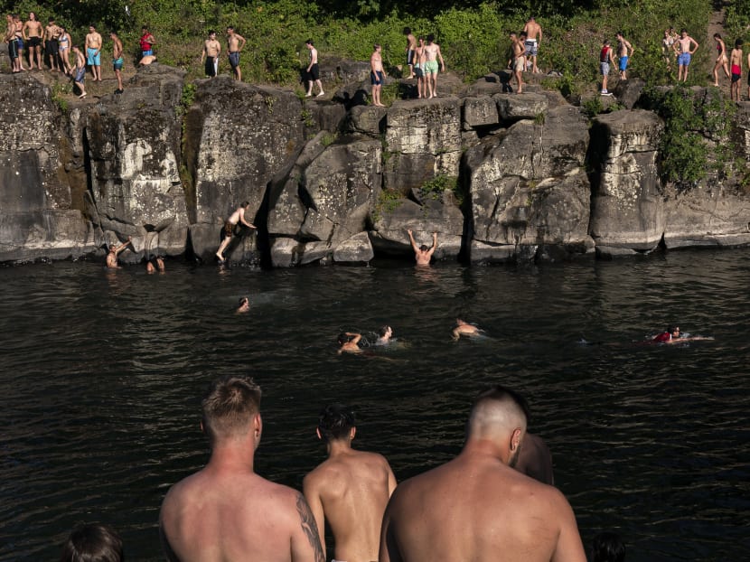 Cliff divers line up along the Clackamas River at High Rocks Park in Portland, Oregon on June 27, 2021. Record breaking temperatures lingered over the Northwest during a historic heatwave over the weekend.