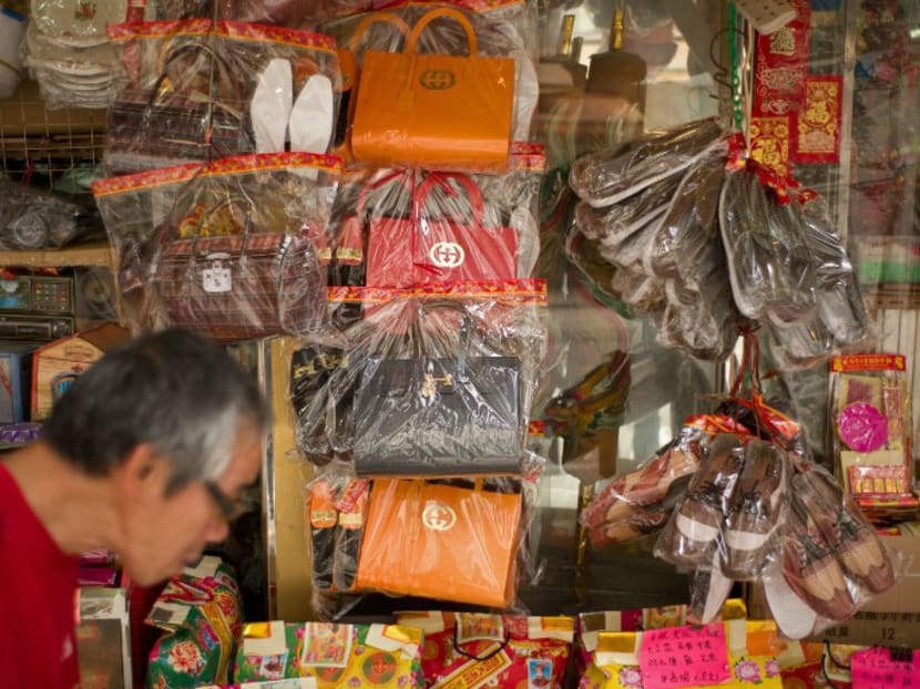 A man walking past a store selling paper replicas of items used as offerings for deceased relatives and displaying paper luxury bags in Hong Kong. Photo: AFP
