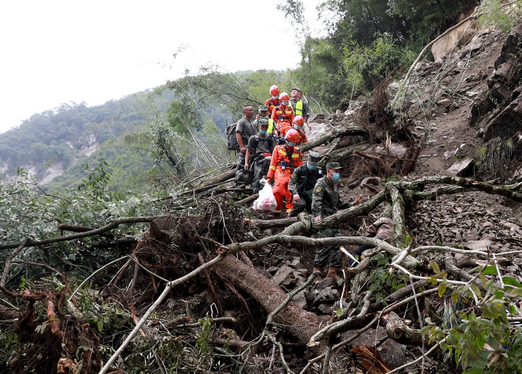 This photo taken on Sept 6, 2022 shows rescuers walking past uprooted trees from a landslide as they head to an earthquake-affected area following the earthquake that struck Sept 5, in Shimian county, Ya'an city, in China's southwestern Sichuan province.
