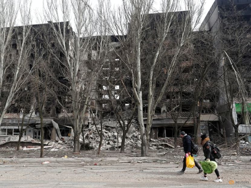 Local residents walk past an apartment building destroyed during Ukraine-Russia conflict in the besieged southern port city of Mariupol, Ukraine March 31, 2022. REUTERS/Alexander Ermochenko