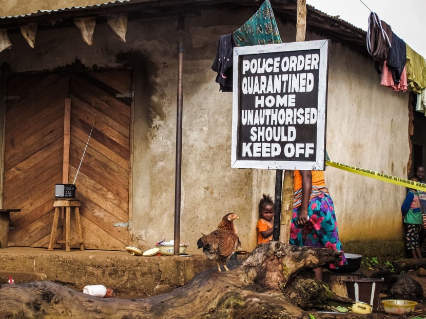A child stands near a sign advising of a quarantined home in an effort to combat the spread of the Ebola virus in Port Loko, Sierra Leone. Photo: AP