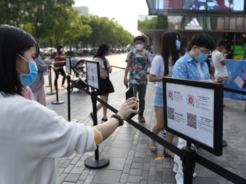 This file photo taken on May 2, 2020 shows a woman wearing a face mask as a preventive measure against the Covid-19 coronavirus as she uses a phone app to scan a code required to prove her health and travel status before being allowed to enter a shopping mall in Beijing.