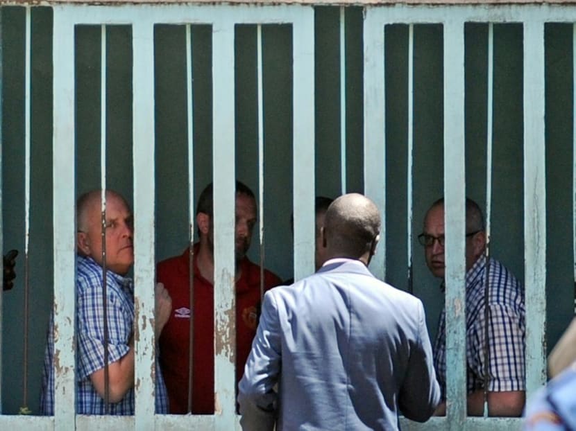 British nationals, (from left) - Eddie Swift, Ian Glover, Paul Abbot (hidden), and Steve Gibson, talk with a lawyer from holding cellsat a magistrates court in the Kenyan capital Nairobi on March 21, 2016, after being ordered -to pay a fine or face a year in a Kenyan jail for photographing aircraft. Photo: AFP