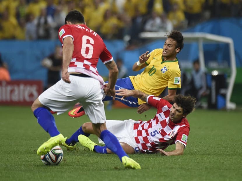 Brazil's forward Neymar (top) falls on Croatia's defender Vedran Corluka (bottom) following a tackle as Croatia's defender Dejan Lovren (front) controls the ball during a Group A football match between Brazil and Croatia at the Corinthians Arena in Sao Paulo during the 2014 FIFA World Cup on June 12, 2014.