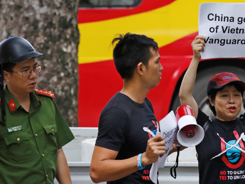 A Vietnamese policeman approaches anti-China protesters as they hold placards during a demonstration in front of the Chinese embassy in Hanoi, Vietnam on Aug 6, 2019.