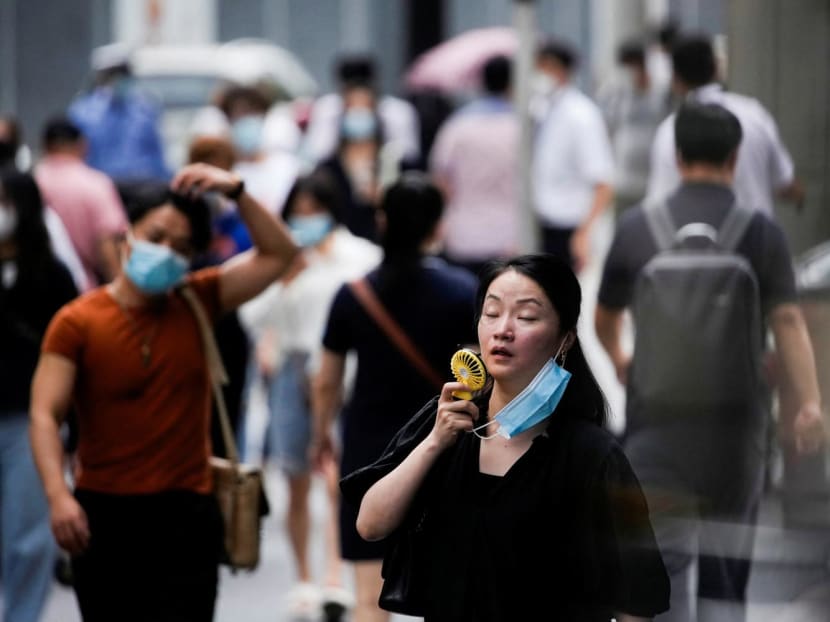 A woman uses a fan as she walks on a street on a hot day in China on July 19, 2022.