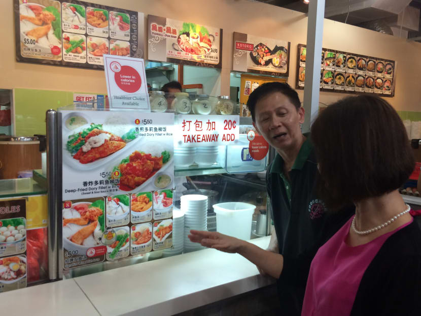 Mr Ken Ng, an F&B tenant in Fusionopolis' Courtyard food court, talking about his healthier sliced fish soup with Senior Minister of State (Health and Manpower) Amy Khor. Photo: Louisa Tang