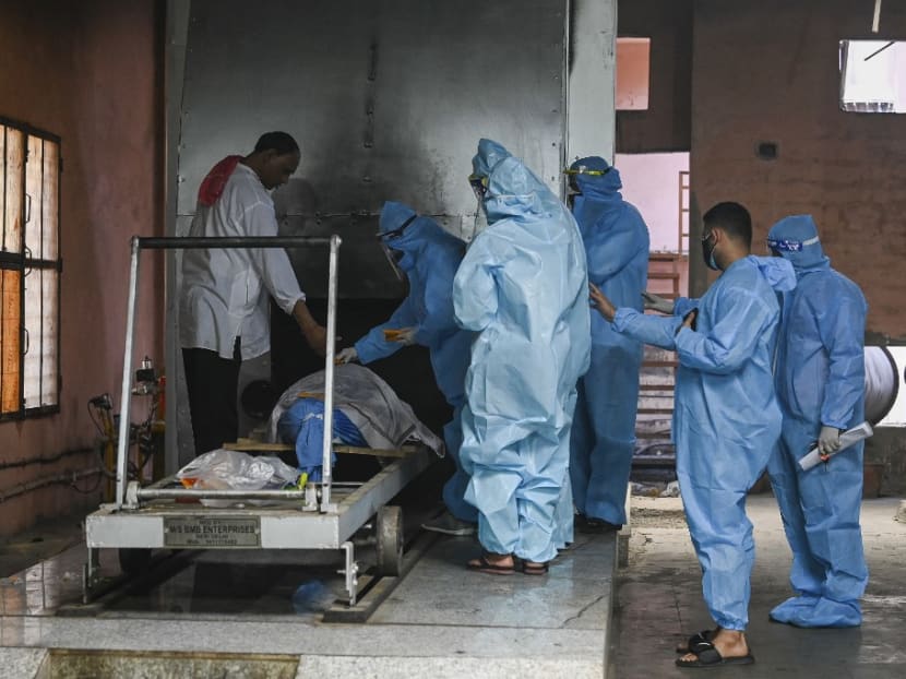 Relatives in wearing personal protective equipment (PPE) suits perform the last rites for their loved one, who died due to the Covid-19 coronavirus, at a crematorium in New Delhi on May 21, 2021.