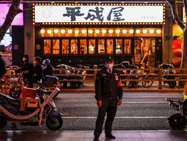 A guard stands on a street next to shops and restaurants in the Jing'an district, in Shanghai on Nov 7, 2022.
