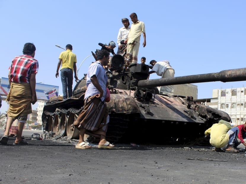 People gather near a tank burnt during clashes on a street in Yemen's southern port city of Aden. Photo: Reuters