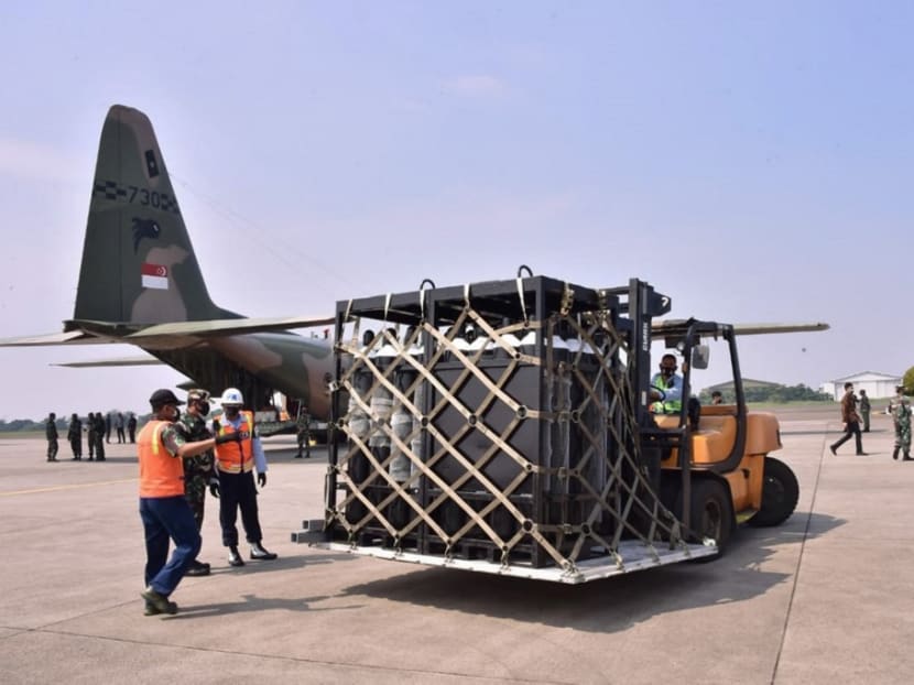 Officers unloading medical equipment, such as oxygen cylinders, ventilators as well as masks, gloves and gowns on two Singapore air force planes, to be used in the Covid-19 coronavirus pandemic, at the air force base in Jakarta, on July 9, 2021.