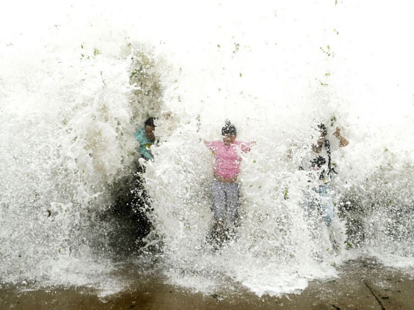 Tourists near the seashore being hit by a wave that surged past a barrier under the influence of Typhoon Chan-hom in Qingdao yesterday. Photo: REUTERS
