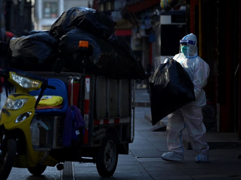A worker wearing personal protective equipment transports garbage bags from the entrance of a hotel in Beijing on Dec 6, 2022.