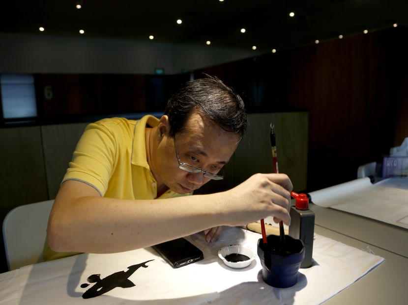 Looking through magnified copies of his Chinese calligraphy reference book on his laptop, Mr Wesley Seah would painstakingly practise his brush strokes before getting feedback from friends. Photo: Raj Nadarajan/TODAY