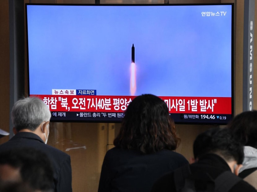 People watch a television screen showing a news broadcast with file footage of a North Korean missile test, at a railway station in Seoul on Nov 3, 2022.