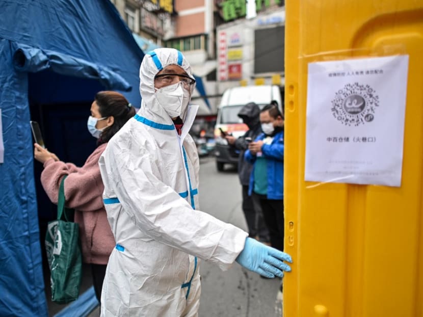 A man wearing a protective suit controls the access to a market in Wuhan, in China's central Hubei province on March 30, 2020, after travel restrictions into the city were eased following more than two months of lockdown due to the Covid-19 coronavirus outbreak.