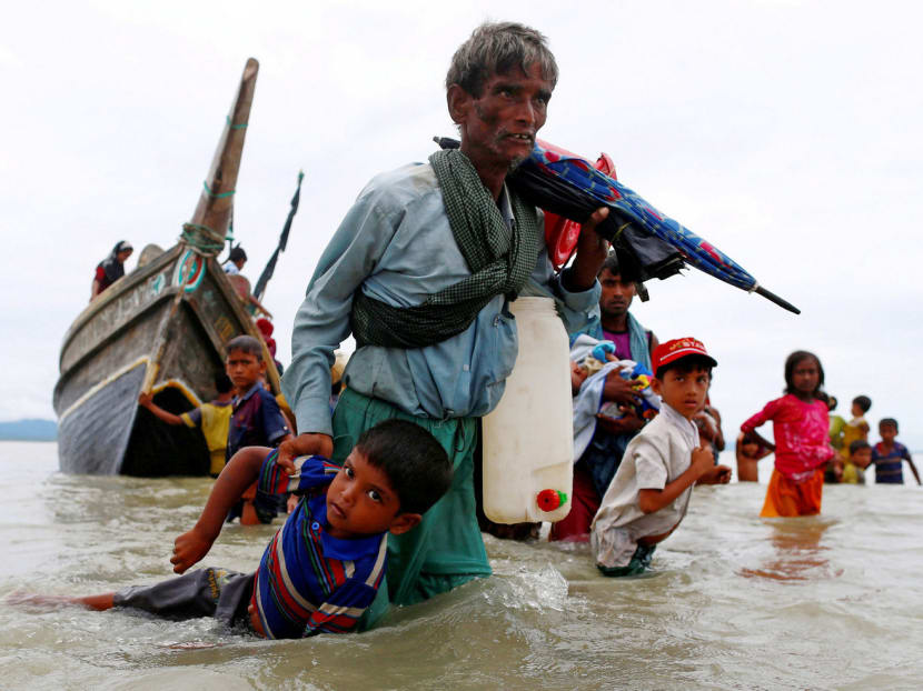 A Rohingya refugee dragging a child to shore after crossing the Bangladesh-Myanmar border by boat, on Sunday. Photo: Reuters