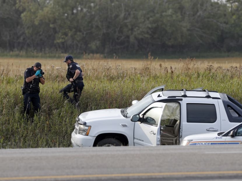 A Royal Canadian Mounted Police officer takes a pictures of police vehicles next to a pickup truck at the scene where suspect Myles Sanderson was arrested, along Highway 11 in Weldon, Saskatchewan, Canada, on Sept 7, 2022.