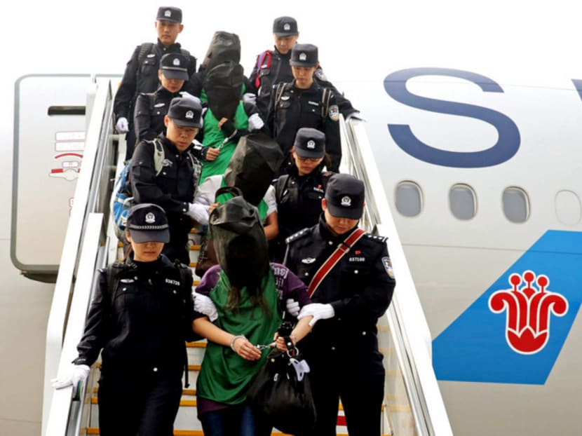 Chinese police escorting a group of people off a plane who were wanted for suspected fraud in China, after they were deported from Kenya. Photo: Reuters