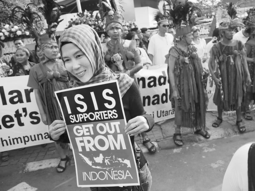 An Indonesian muslim women hold a poster  outside the Starbucks cafe where Thursday's attack took place in Jakarta, Indonesia, Sunday, Jan. 17, 2016. Indonesian police said Saturday they have arrested a number of people suspected of links to the audacious attacks by suicide bombers and gunmen on Thursday in central Jakarta, the first major assault by militants in Indonesia since 2009. (AP Photo/Achmad Ibrahim)