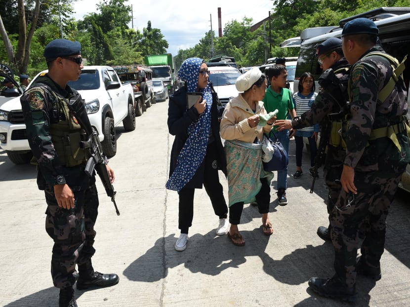 Philippine policemen check evacuees from Marawi aboard a van at a checkpoint. Photo: AFP