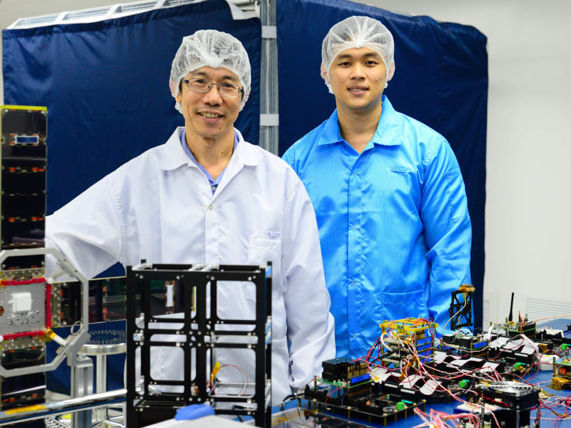 NTU Assoc Prof Low Kay Soon (left) with research engineer Lau Zi Rui, with the chassis of Velox-II and its internal components on the laboratory table. The Velox-I, an older model which has completed its mission in space, is on their right. Photo: NTU