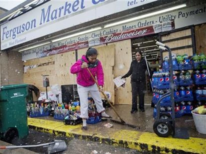 Ms Anjana Patel cleans up the damage from Monday's riots at her store, Ferguson Market and Liquor, Wednesday, Nov 26, in Ferguson. Photo: AP
