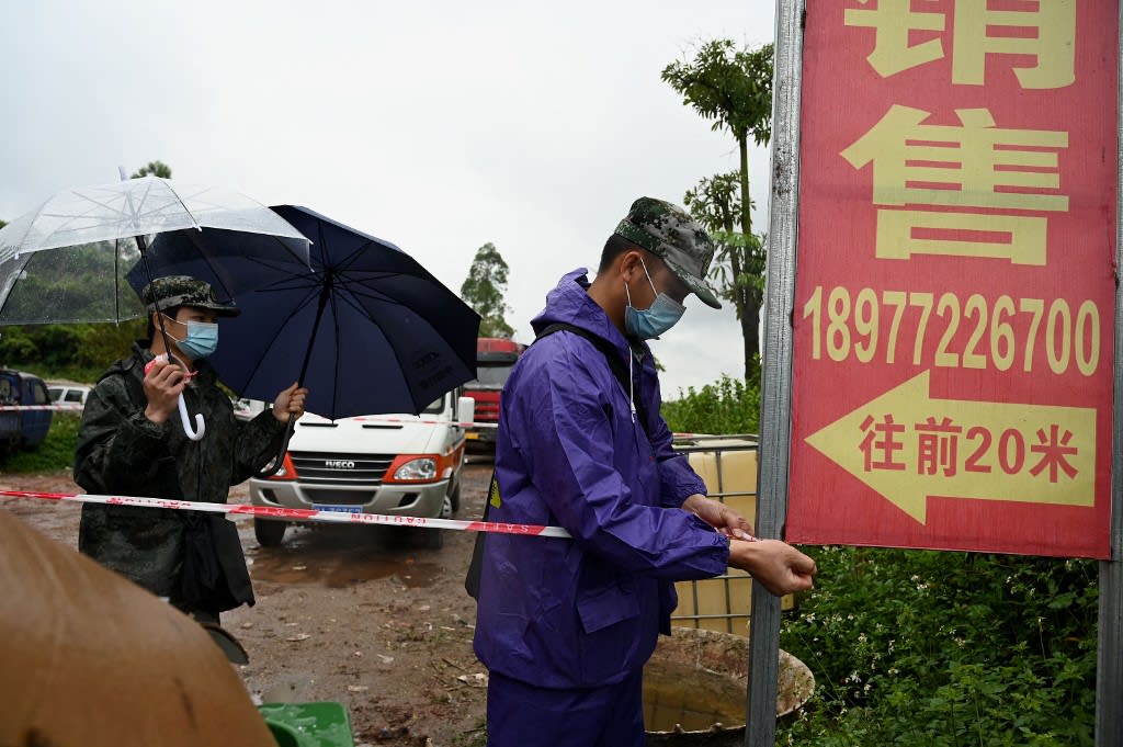Security personnel use perimeter tape to cordon off the entrance to Lv village which leads to the crash site of China Eastern flight MU5375 in Wuzhou in southwestern China's Guangxi province on March 23, 2022.