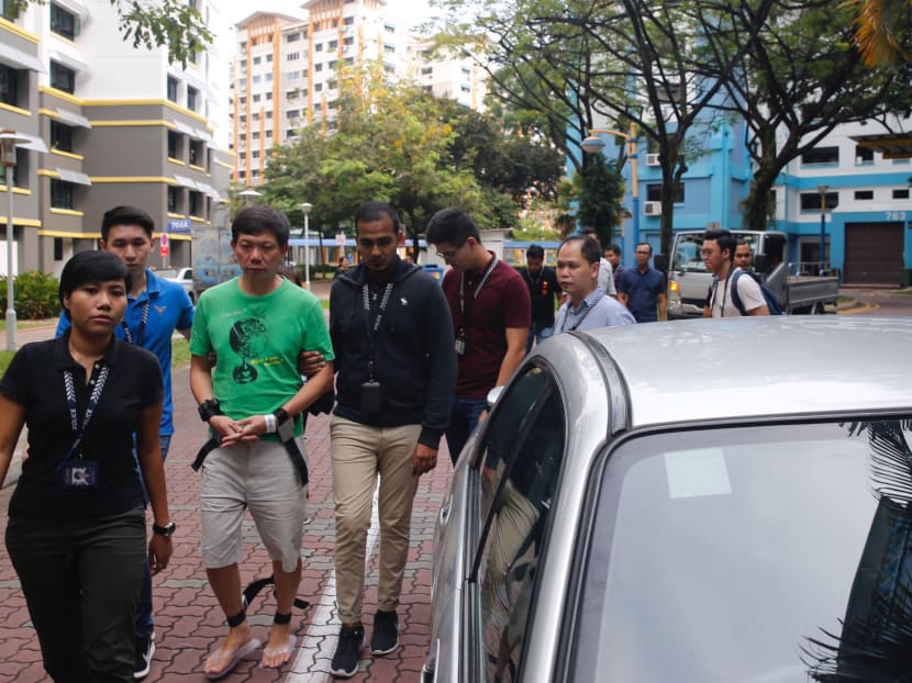 The suspect, believed to be Mr Samuel Tan Joo Soon (in green), was arrested for four offences - possessing an arm without licence, possessing a dangerous instrument, committing a rash act and mischief. Photo: Najeer Yusof/TODAY