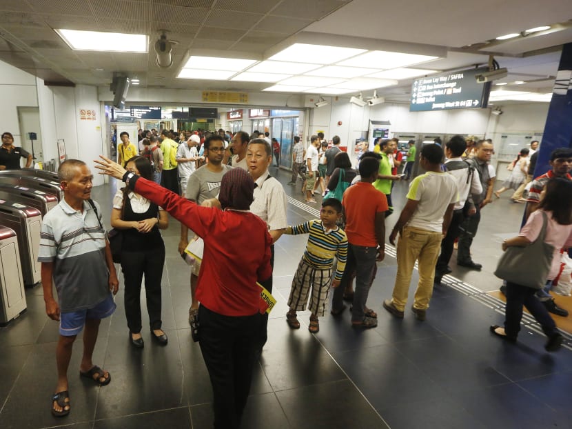 An SMRT employee directing commuters at Boon Lay Station to alternative transport services on July 7, 2015, after train services on the North-South and East-West lines were disrupted. TODAY file photo