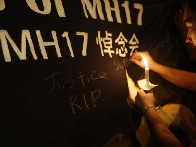 A man writes messages on a banner during a candlelight vigil for victims aboard downed Malaysia Airlines Flight MH17, near Chinatown, in Kuala Lumpur, on July 20, 2014. Photo: Reuters