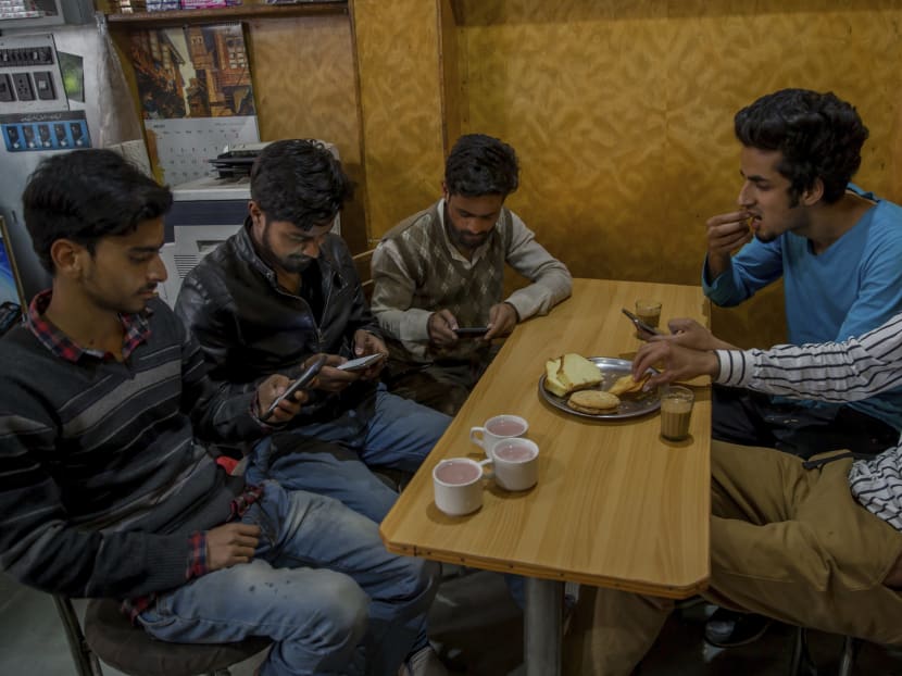 Kashmiri students browse internet on their mobile phones as they sits inside a restaurant in Srinagar, Indian controlled Kashmir. Authorities ordered internet service providers to block 16 social media sites, including Facebook and Twitter, and popular online chat applications for one month "in the interest of maintenance of public order". Photo: AP